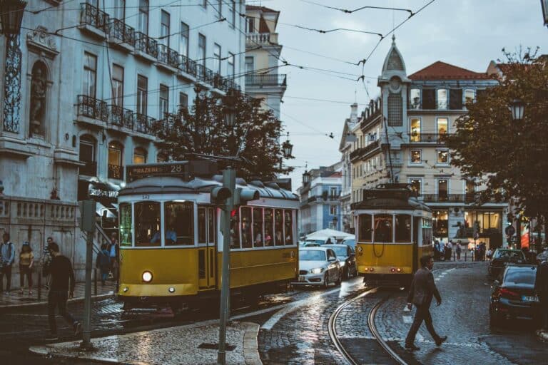 Scenic view of trams navigating the charming streets of Lisbon at dusk, capturing urban life and transportation.
