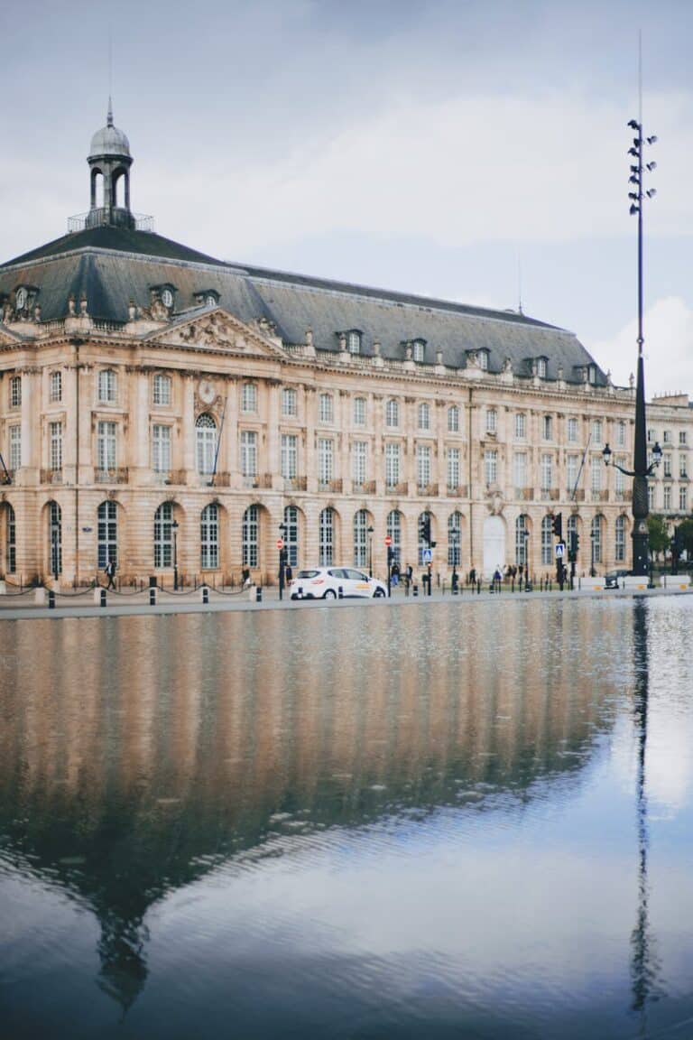 Elegant historic building in Bordeaux reflected in calm water, showcasing architecture.